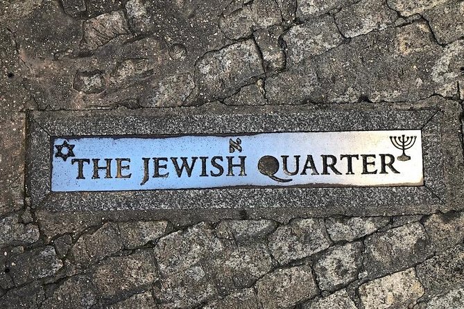 A ceramic street plaque reading The Jewish Quarter set into a stone wall in Toledo