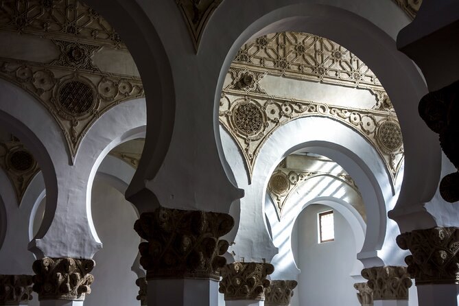 Horseshoe arches on white pillars with deeply carved capitals in a Mudéjar interior in Toledo