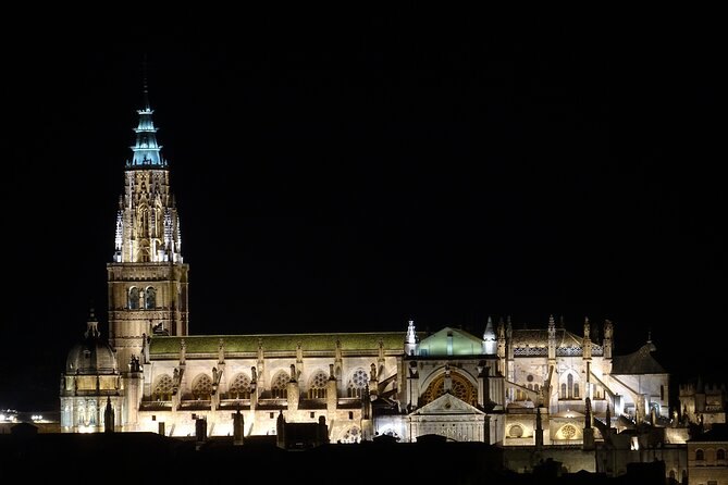 Toledo Cathedral floodlit against a black sky, the spire lit from below
