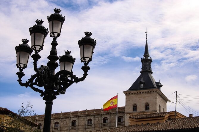 A wrought-iron streetlamp against one of the Alcázar's corner towers and the Spanish flag